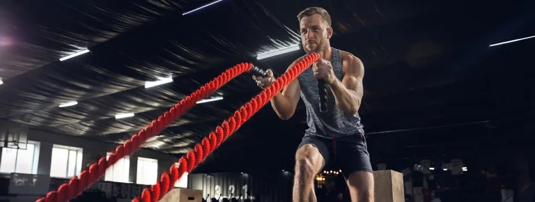 An athlete exercising with battle ropes in a gym