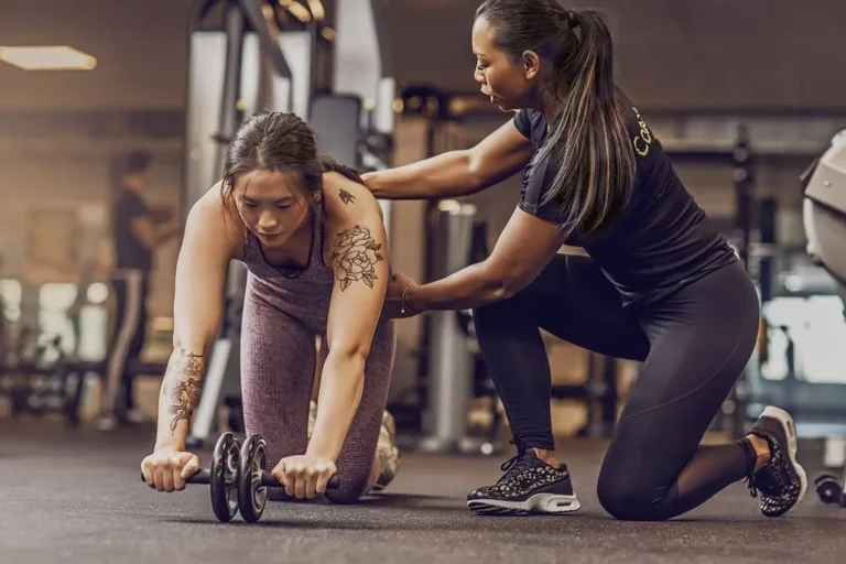 A trainer assisting a client with a floor stretch