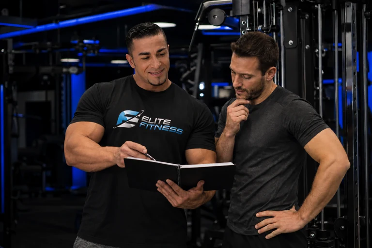 Elie Merhi reviewing a workout plan in an open notebook with a client